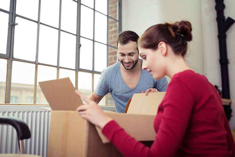 Zwei Personen packen ambitioniert etwas aus einem Karton aus.